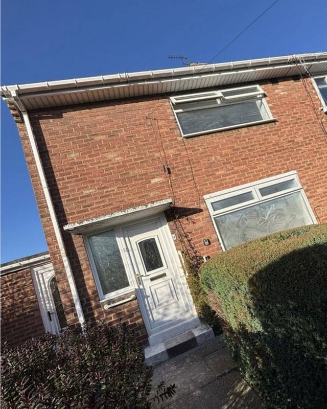 Brick two-bed house with a white front door and hedge